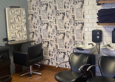 Stylish interior at Aquaintance Hair Salon, Darlington, England featuring vintage wallpaper and modern chairs.