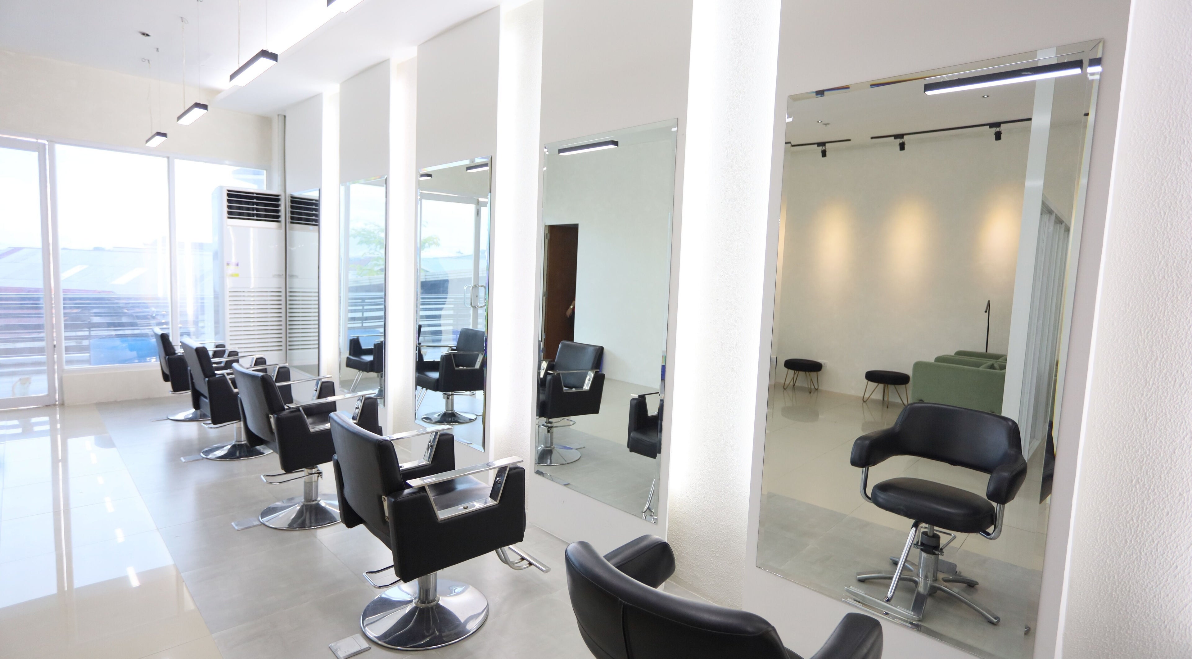 Modern interior of HelloMello Salon in Angeles, Central Luzon, PH with sleek black chairs and mirrors.