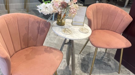 Elegant seating area at Avenue Boutique in Bingley, England, with plush pink chairs and a floral centerpiece.