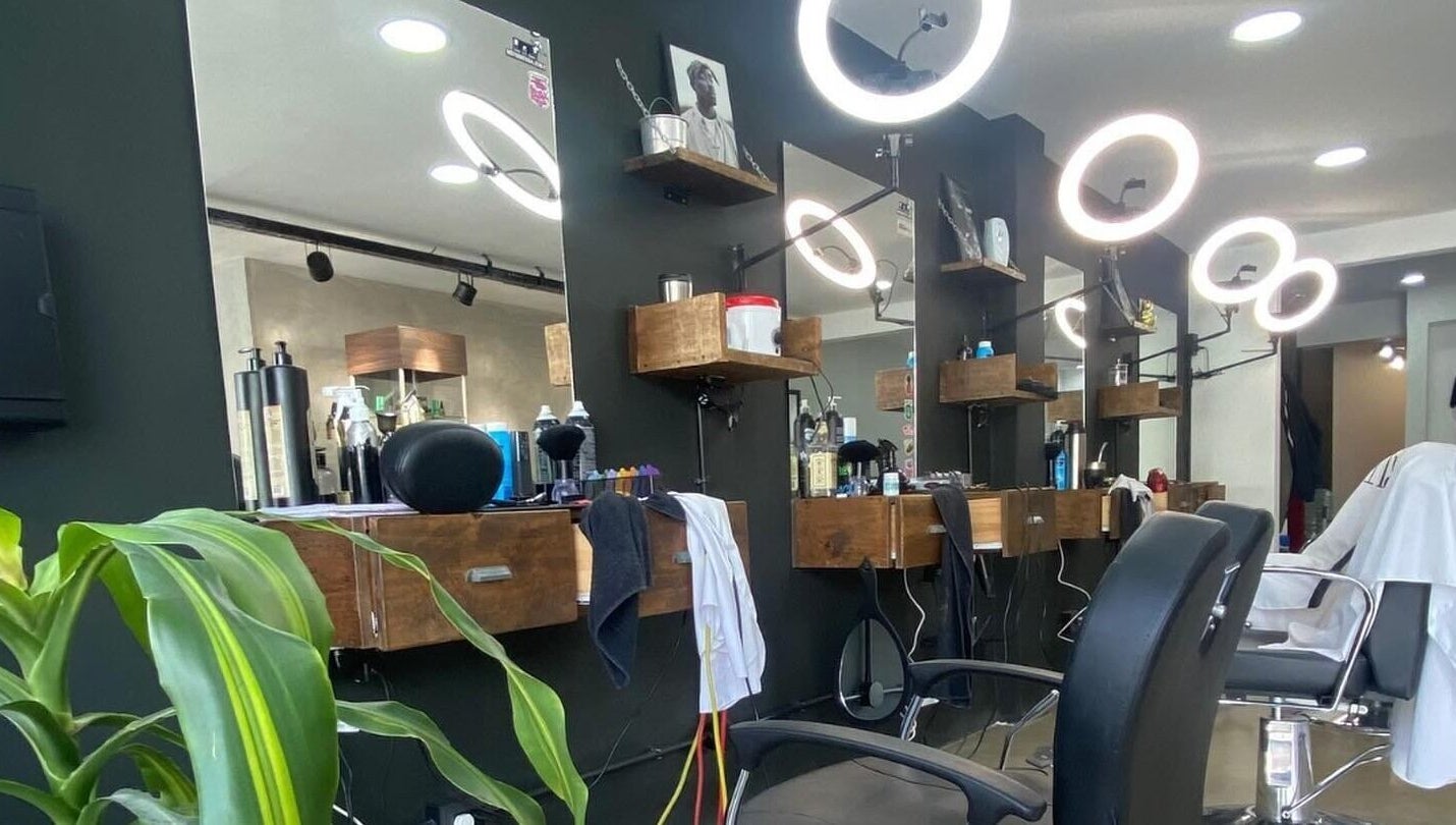 Interior moderno de Barberia Palermo's en Castelar, Provincia De Buenos Aires, AR con sillas elegantes y espejos iluminados.