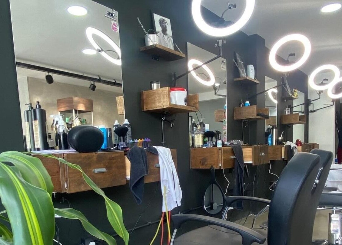 Interior moderno de Barberia Palermo's en Castelar, Provincia De Buenos Aires, AR con sillas elegantes y espejos iluminados.