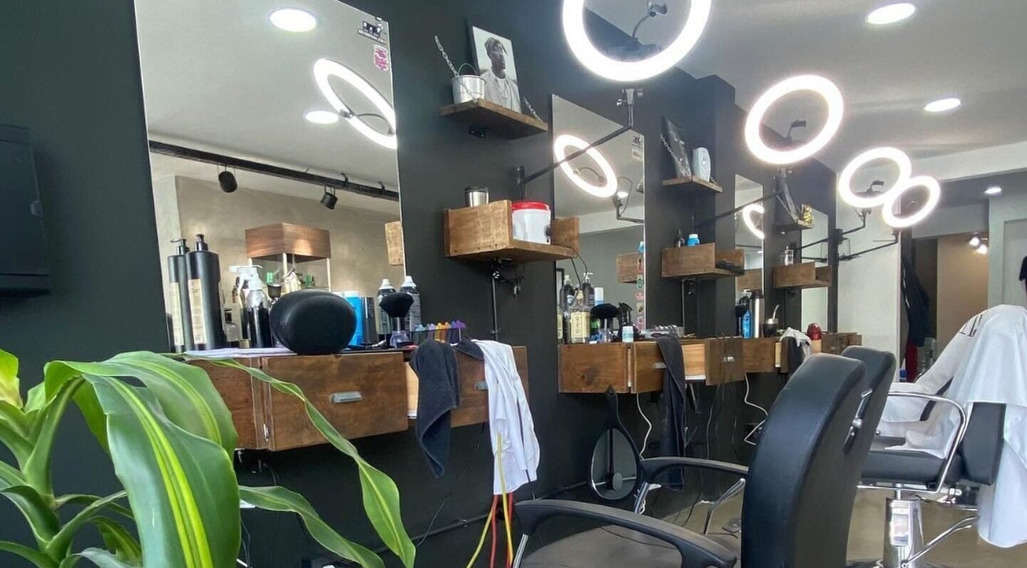 Interior moderno de Barberia Palermo's en Castelar, Provincia De Buenos Aires, AR con sillas elegantes y espejos iluminados.