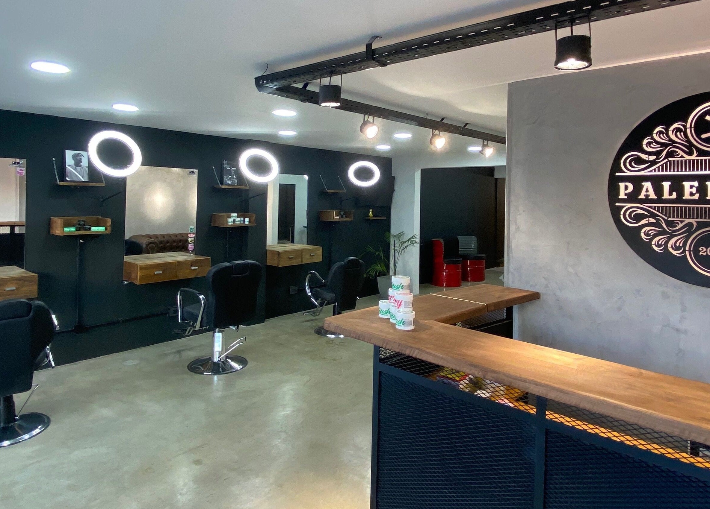 Interior moderno de Barberia Palermo's, Castelar, Provincia De Buenos Aires, AR, con espejos y sillas negras.