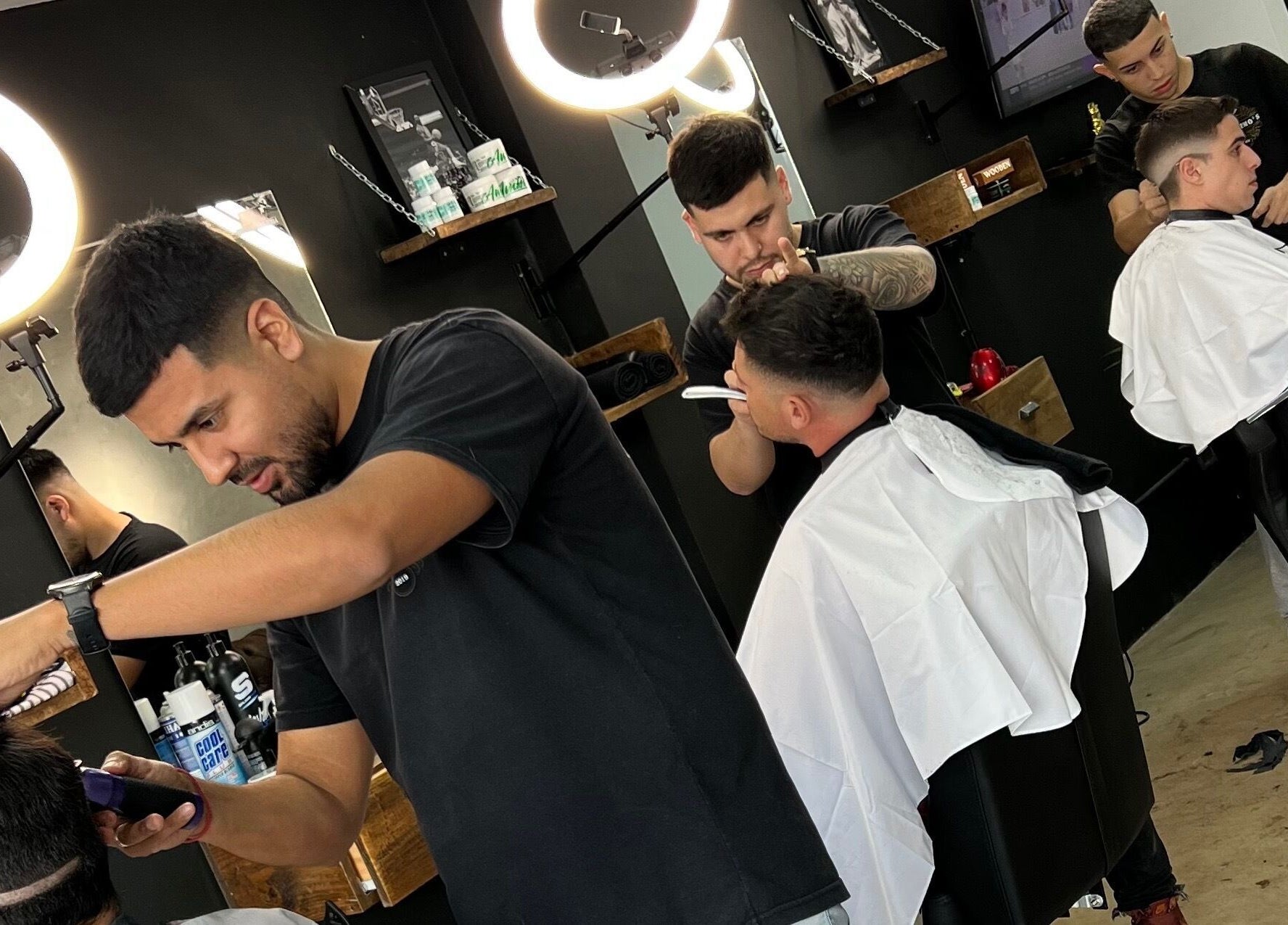 Barberos estilizando cortes de cabello en Barberia Palermo's, Castelar, Provincia De Buenos Aires, AR.