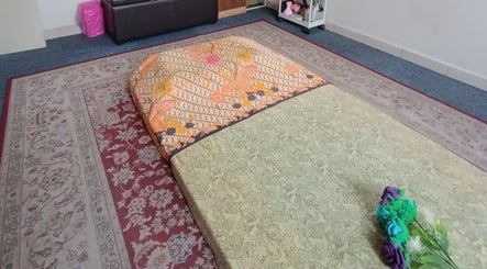 Traditional spa setup at Tusuk Jari Pulau Pinang, Bukit Mertajam with cozy mat and flowers.