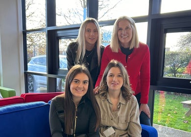 Team at Escape Hair, Strensall, England, GB, smiling indoors with bright natural light through windows.