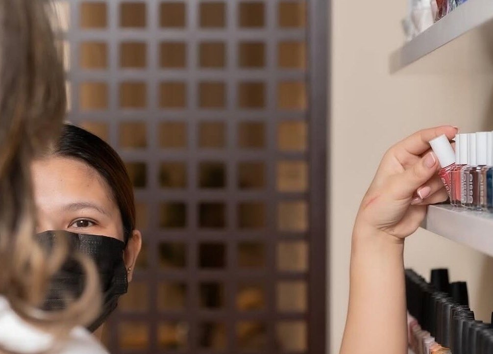 Customer selects nail polish color at Anamil Spa - Al Rabi, Riyadh, Riyadh Province, SA. Expert care offered.