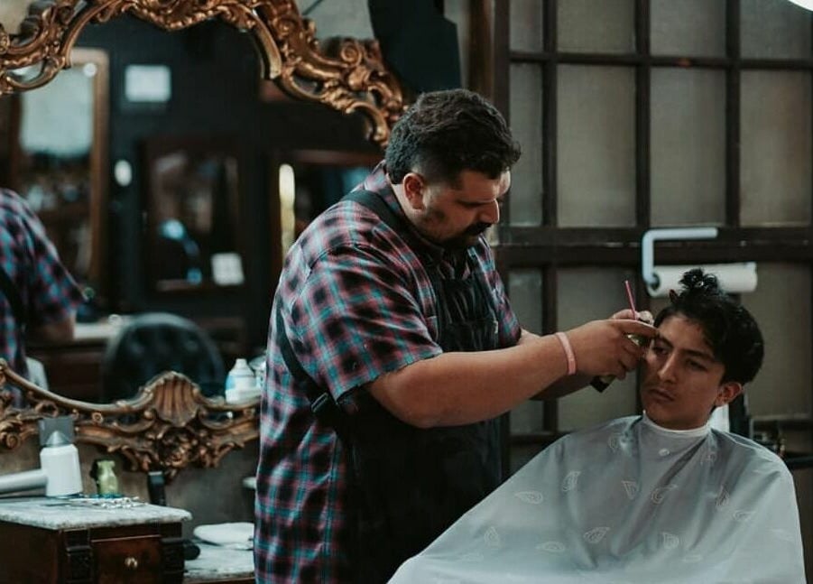 Barber expertly styling at Vosco’s Barbershop in Logan, Utah, US, showcasing vintage decor and grooming skills.