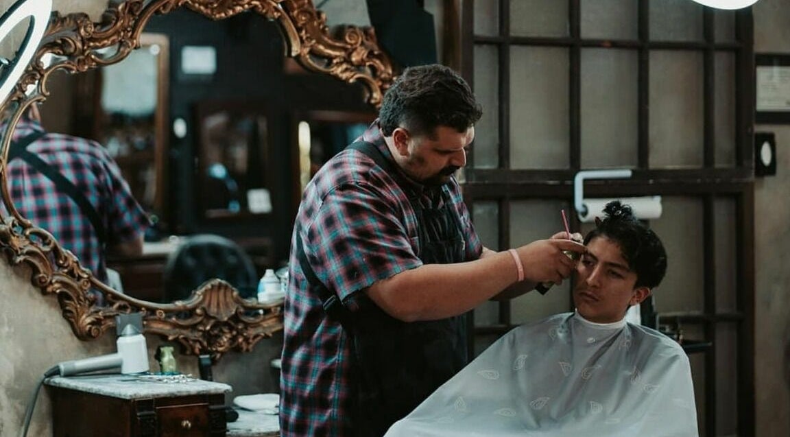 Barber expertly styling at Vosco’s Barbershop in Logan, Utah, US, showcasing vintage decor and grooming skills.