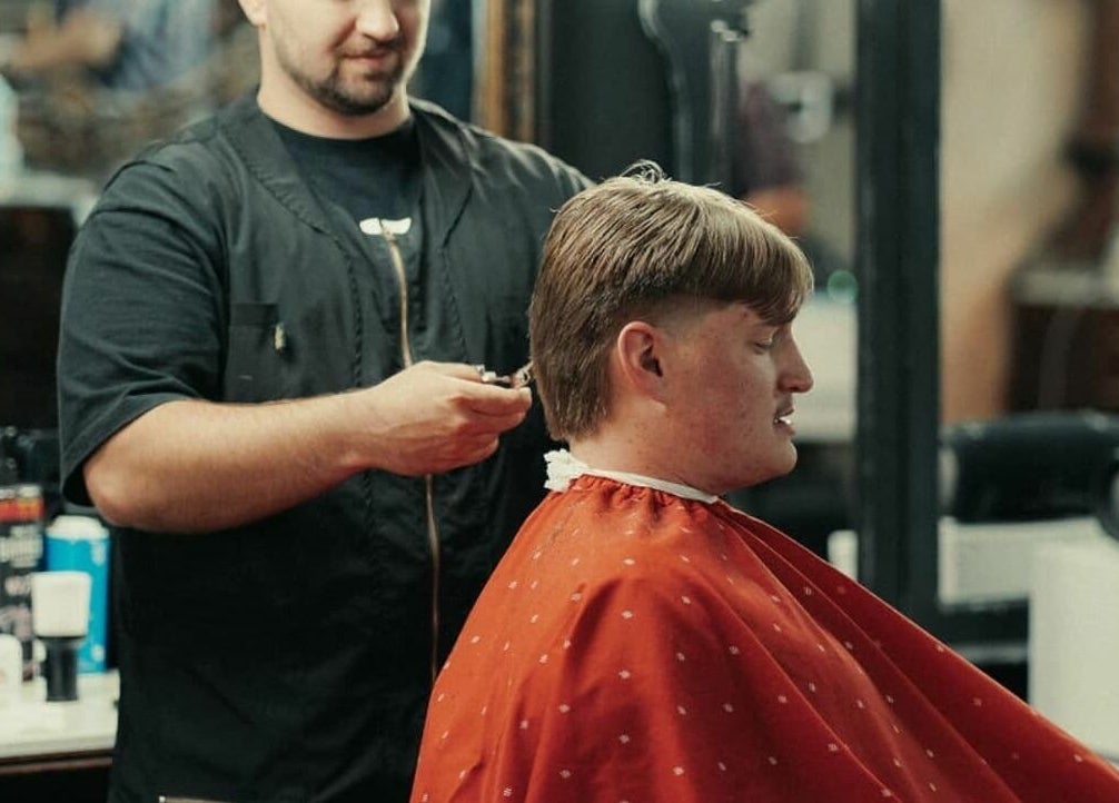 Stylist giving a haircut at Vosco’s Barbershop in Logan, Utah, US, enhancing a client’s look with precision.