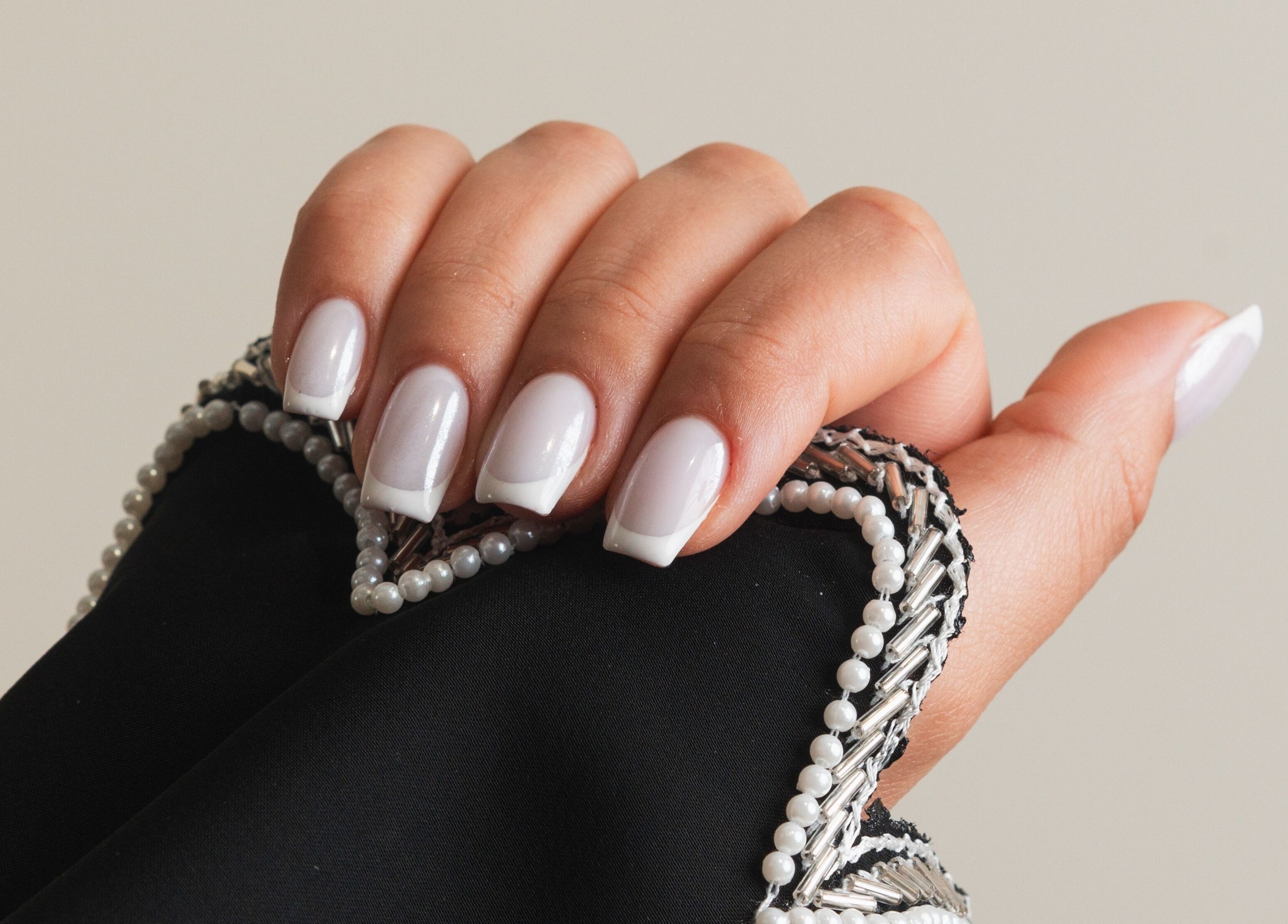Close-up of elegant French manicure at The Hideaway, Dubai, AE, showcasing pearl-embellished sleeve.