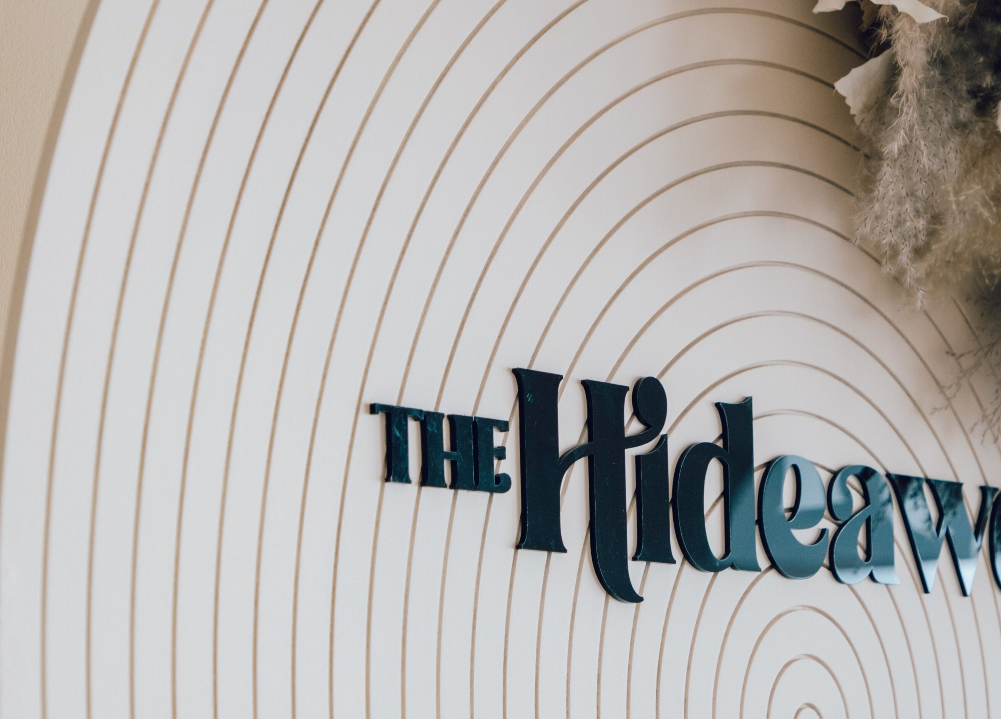 Elegant sign for The Hideaway in Dubai, AE, featuring curved design elements.