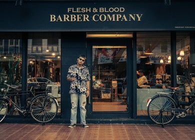 Exterior of Flesh & Blood Barber Company in Kuantan, Pahang, MY with vintage bikes and stylish visitor.
