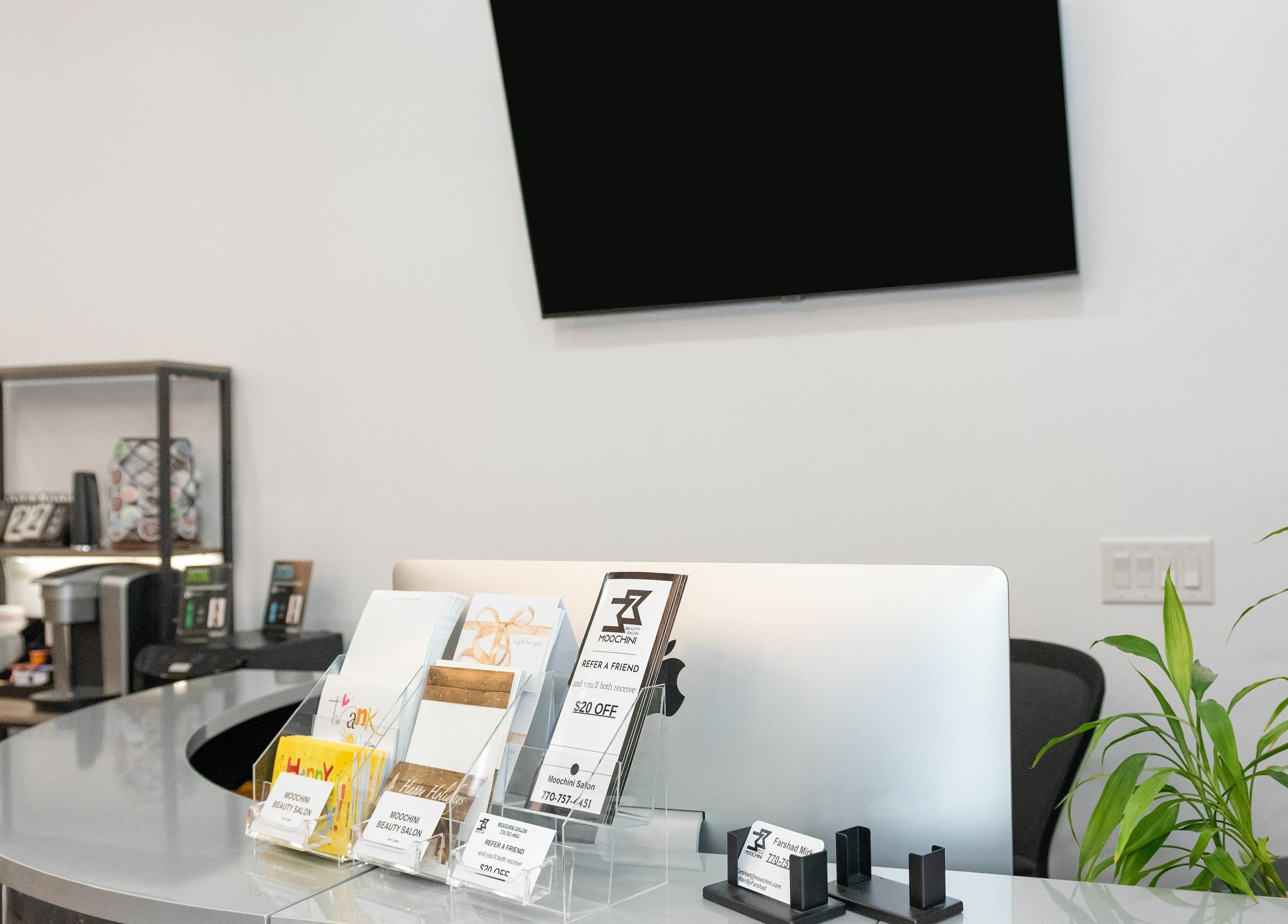 Reception desk at Moochini Hair Salon in Alpharetta, Georgia, US featuring promotional materials and sleek decor.