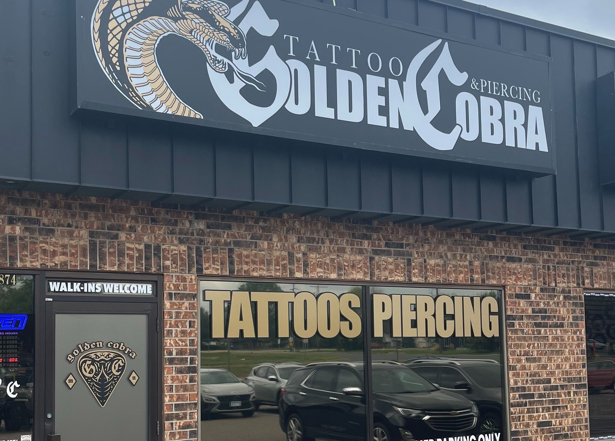 Front view of Golden Cobra Tattoo and Piercing in Fridley, Minnesota, US, showcasing bold signage.
