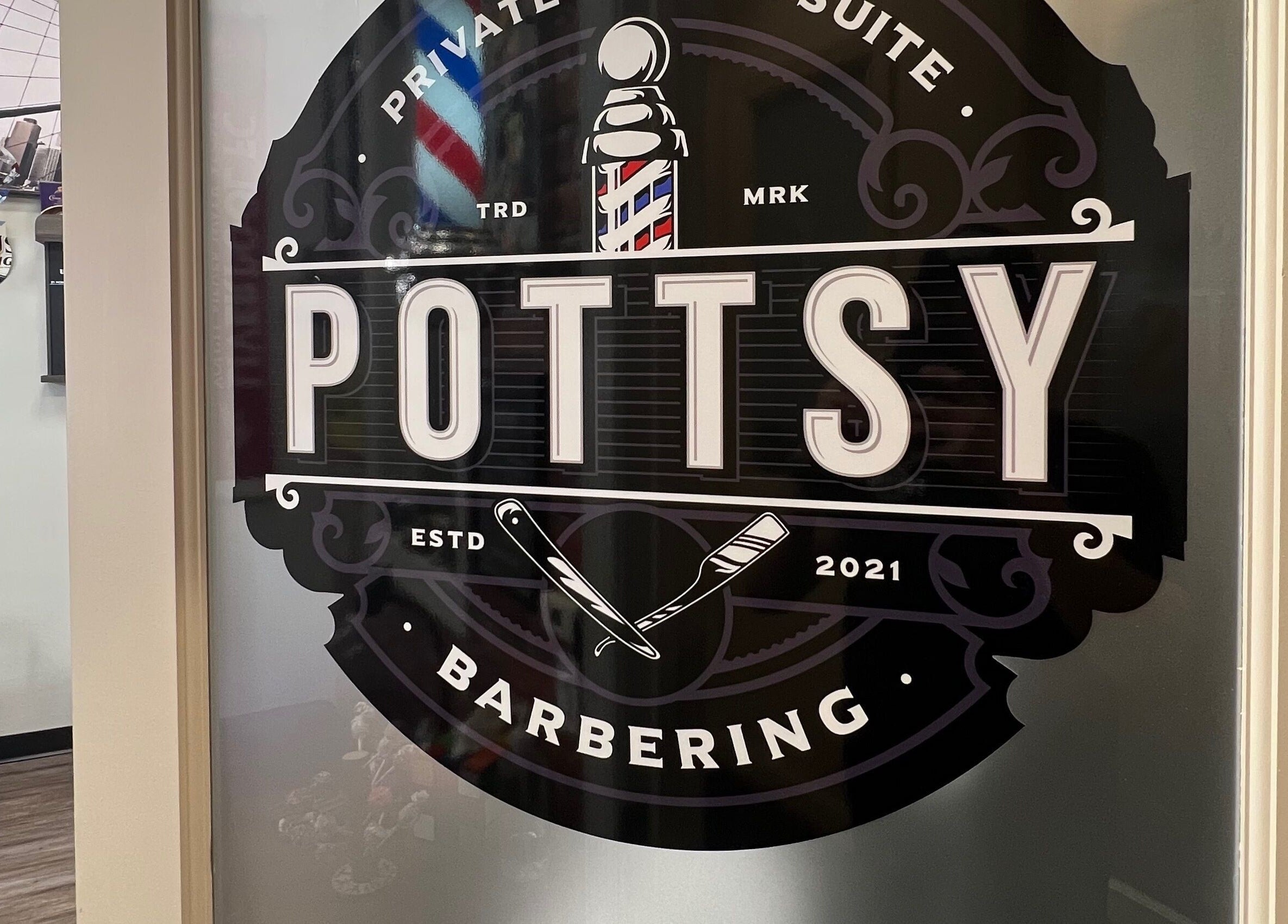 Logo of Pottsy Barber Suite on a glass door in Cinnaminson, New Jersey, US, showcasing vintage barber tools.