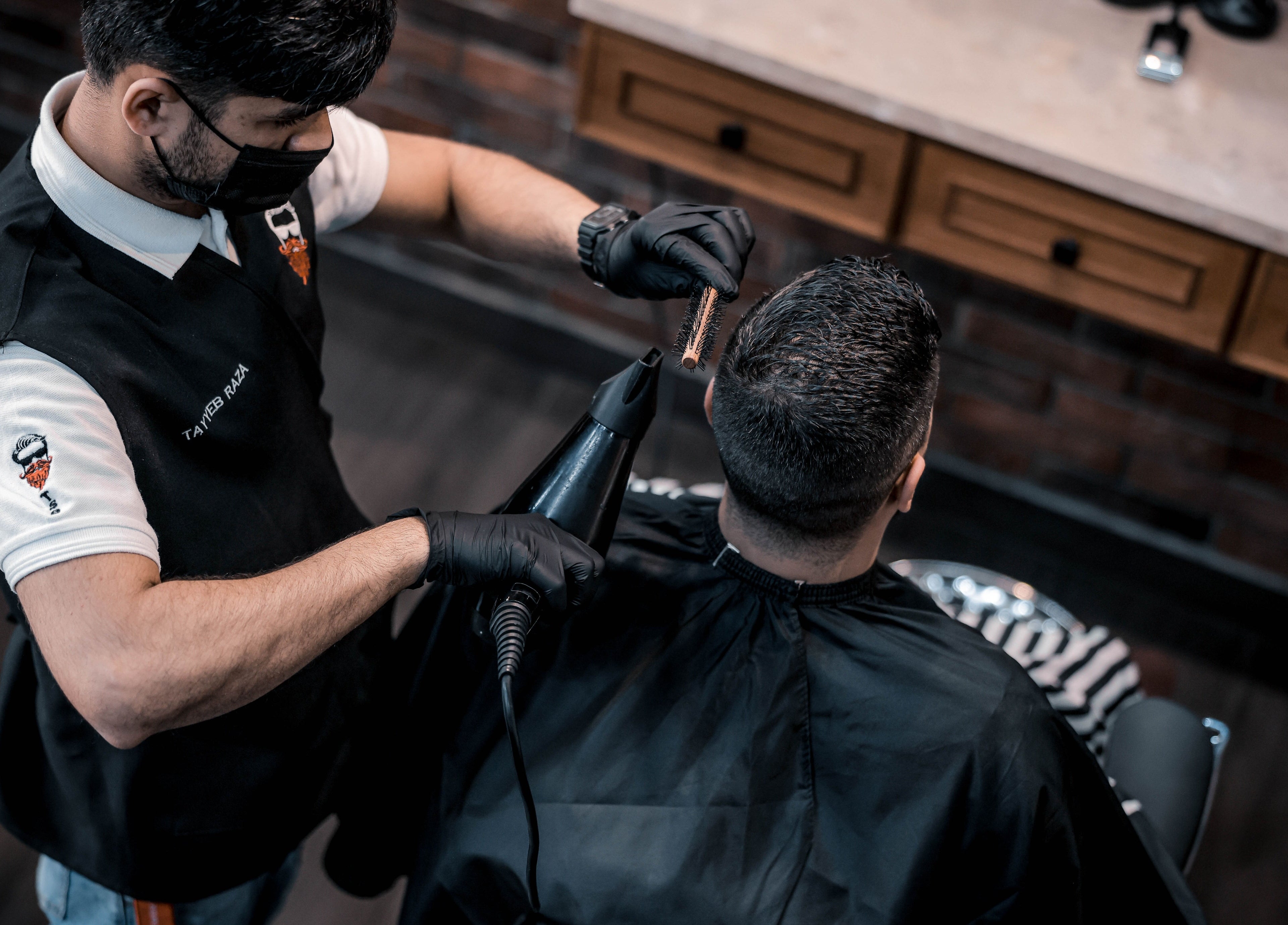 Stylist at The Stars Barber in Dubai, AE expertly trims client's hair with precision and care.