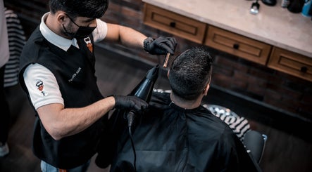 Stylist at The Stars Barber in Dubai, AE expertly trims client's hair with precision and care.