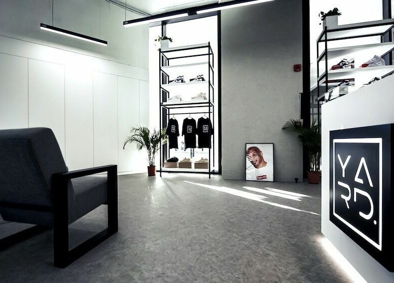 Chic interior of YARD Barber and Shop in Dubai, AE showcasing stylish decor and clothing display.