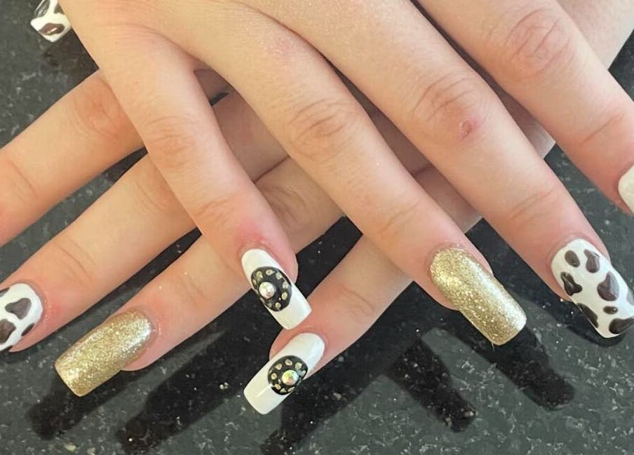 Stylish nail art at mkrnails&beauty academy in Kippax, England, GB featuring cow patterns and gold glitter.