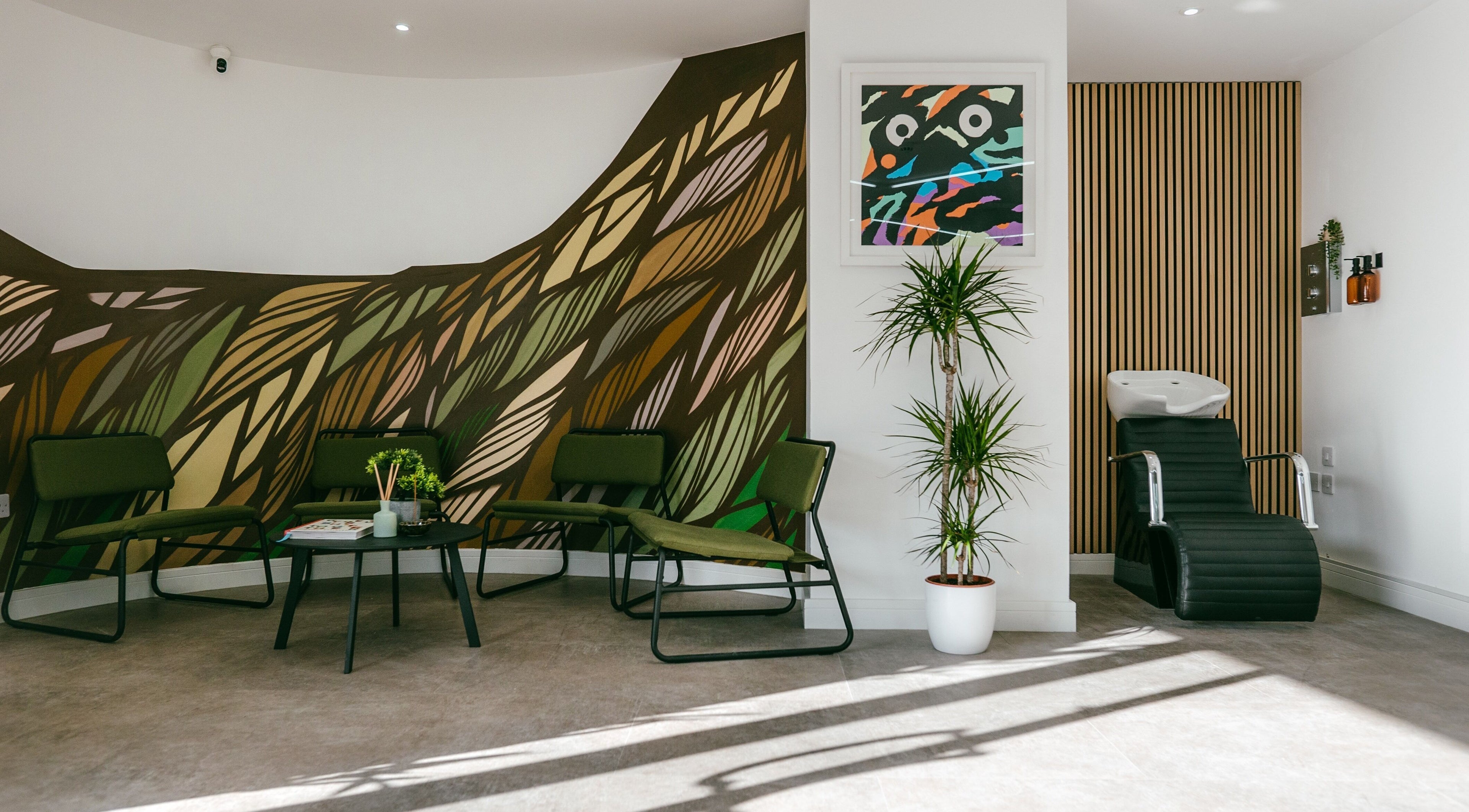 Modern lounge area at Mr Tillys Barbershop Chillingham Road, Newcastle upon Tyne, England, GB with colorful wall art.