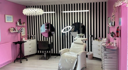 Interior of Bloom Nails and Beauty in Rochdale, England, with pink walls, striped decor, and modern salon chairs.