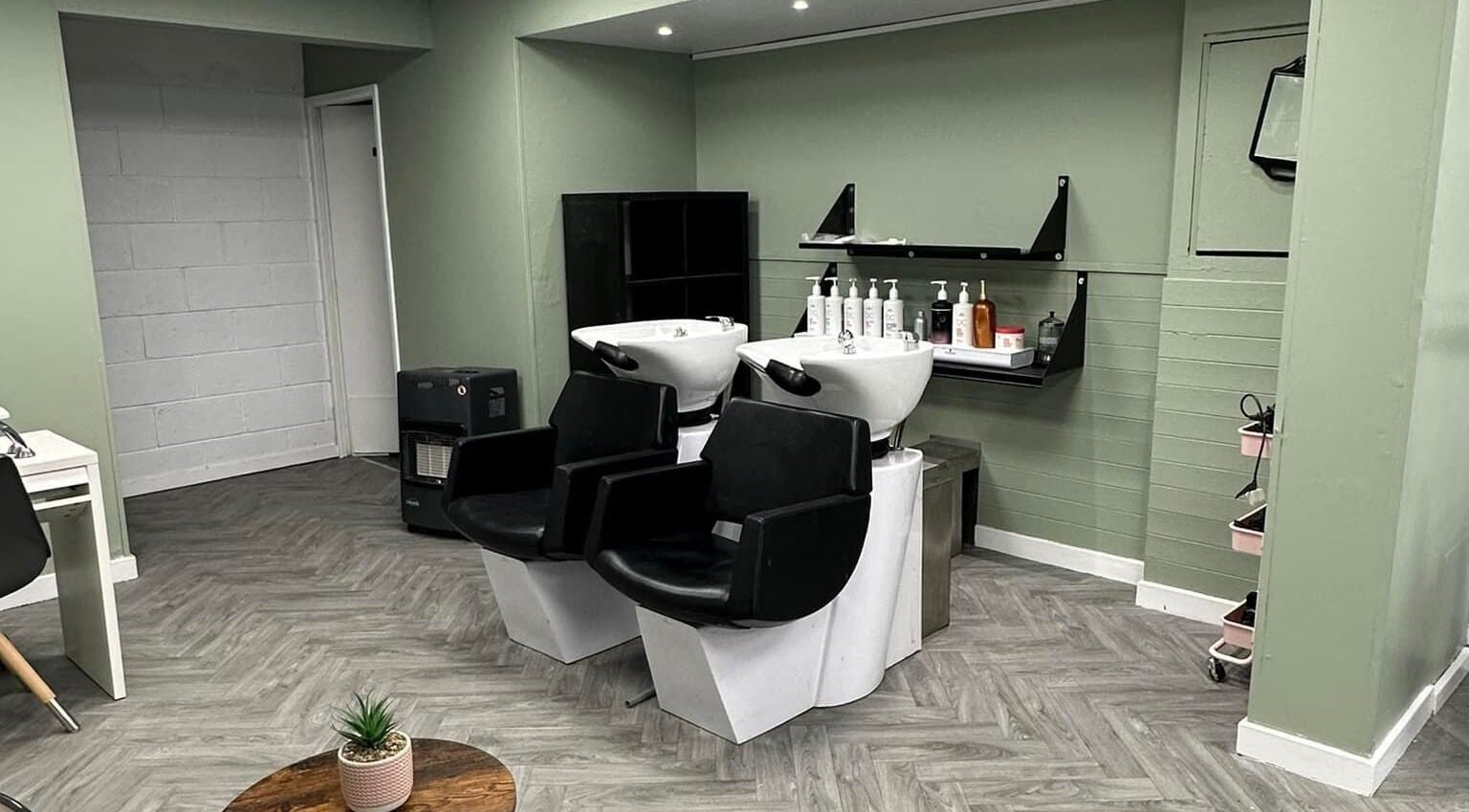 Modern shampoo stations at Ivy Studio, Shaw, England, GB. Elegant design with sleek chairs and product shelves.
