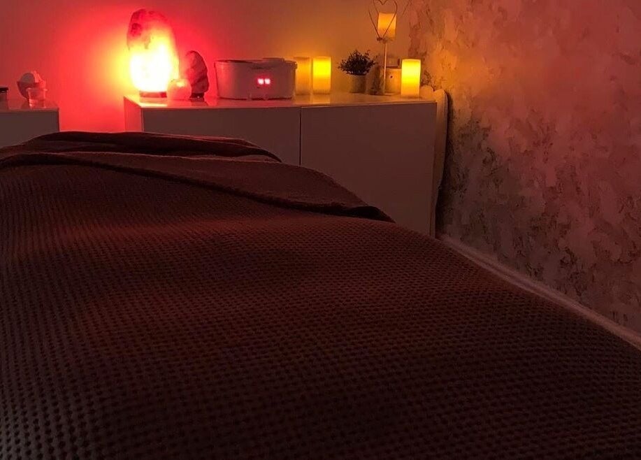 Tranquil massage room at Platinum Beauty, Littleborough, England, GB, with ambient red lighting and cozy bed.