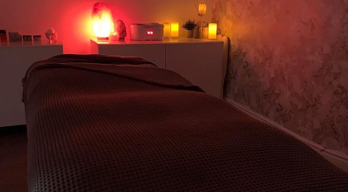 Tranquil massage room at Platinum Beauty, Littleborough, England, GB, with ambient red lighting and cozy bed.