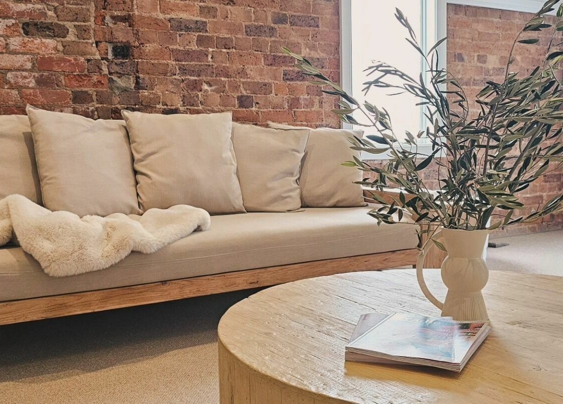 Cozy lounge area at Slow by Seed in Orange, New South Wales, AU with a plush sofa and rustic table.