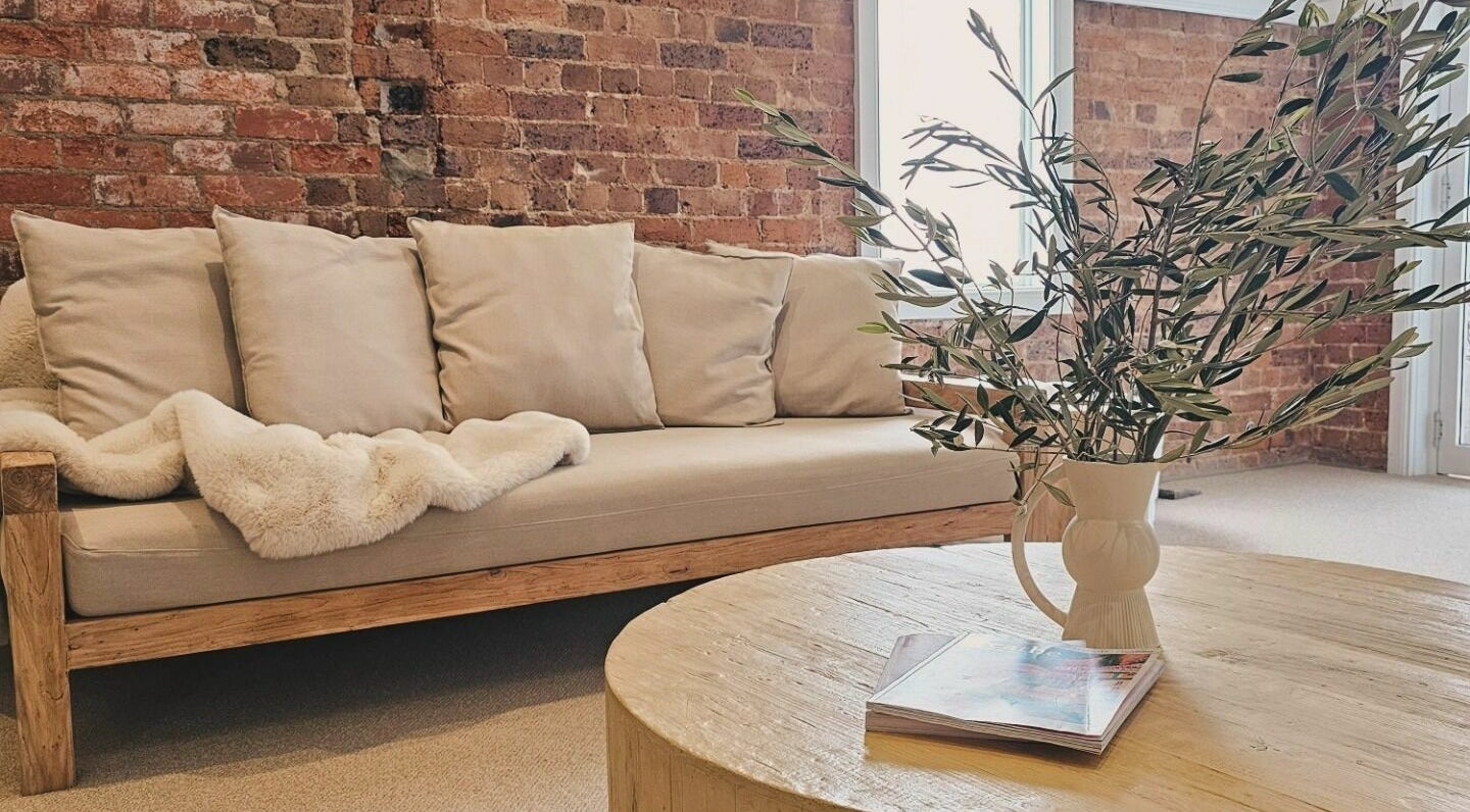 Cozy lounge area at Slow by Seed in Orange, New South Wales, AU with a plush sofa and rustic table.