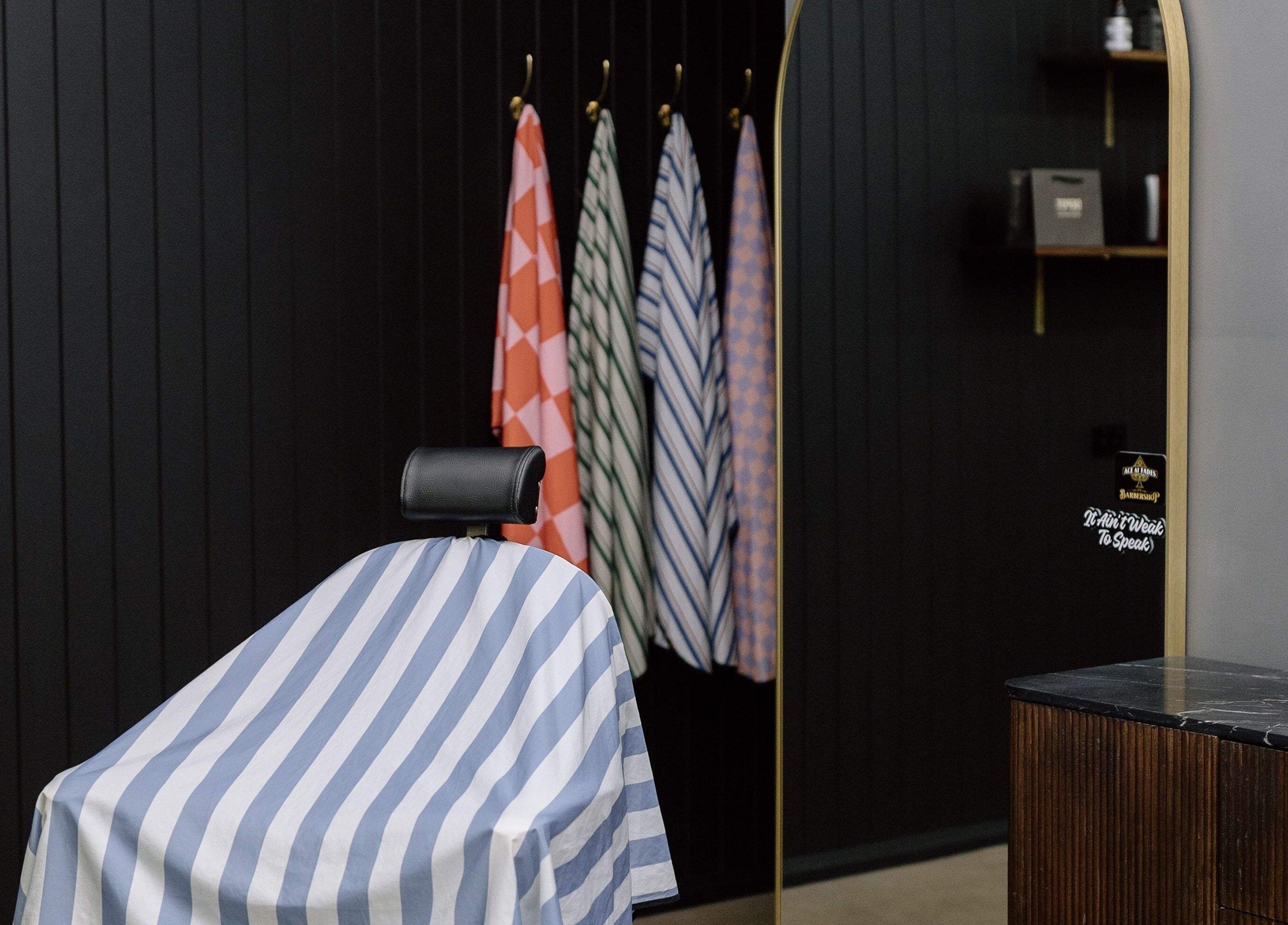 Stylish barber chair at Ace At Fades, Dubbo, New South Wales, AU with colorful hanging capes.