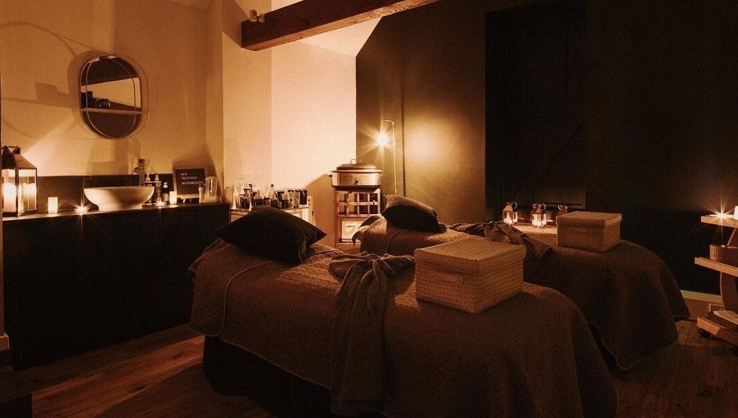 Cozy treatment room at Reading Room Day Spa in Lewes, England, GB, with candle lighting and plush beds.