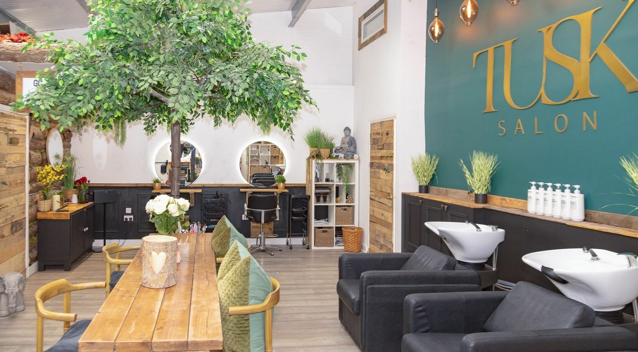 Modern interior of Tusk Salon in Moreton, England, GB, featuring chic decor and lush indoor greenery.