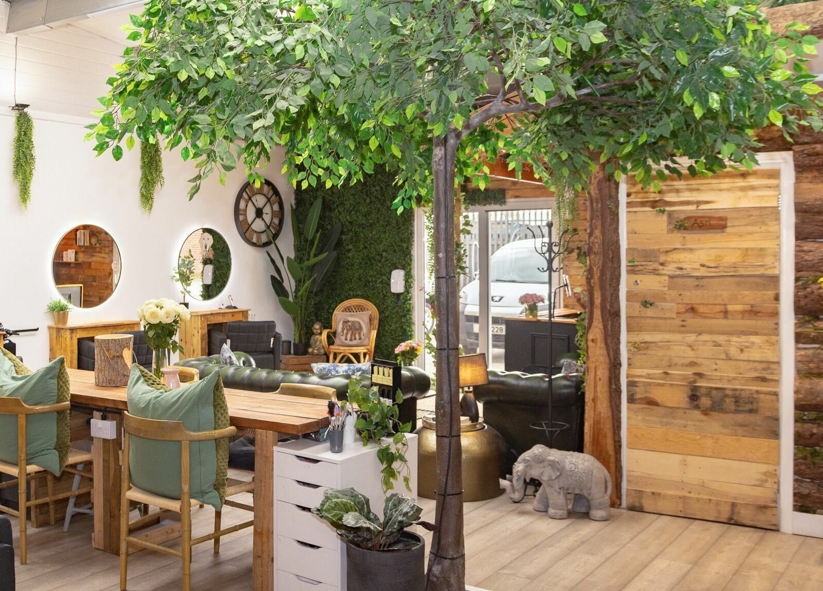 Bright, modern interior of Tusk Salon in Moreton, England, GB, featuring lush greenery and chic rustic decor.