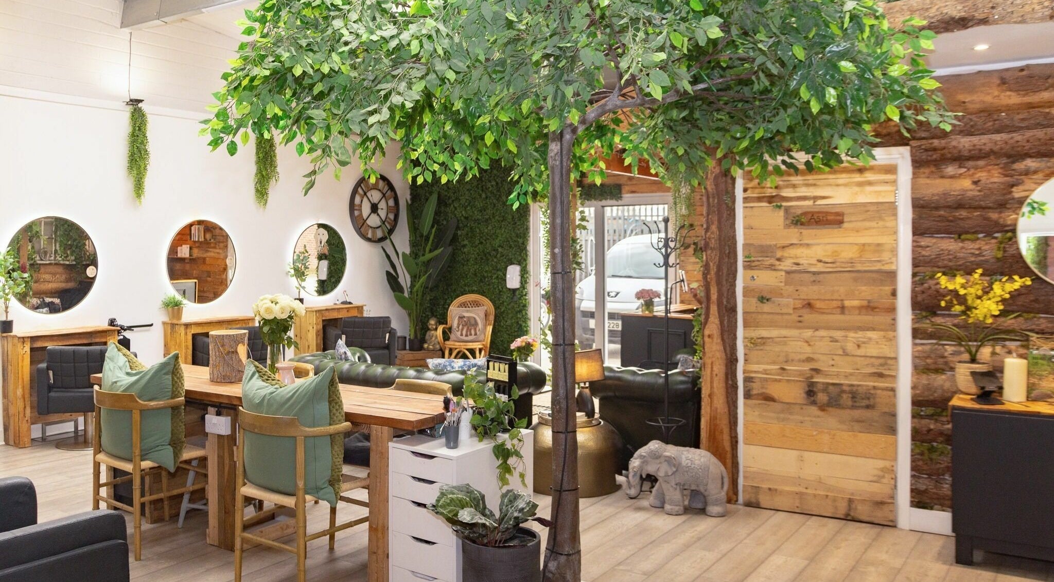 Bright, modern interior of Tusk Salon in Moreton, England, GB, featuring lush greenery and chic rustic decor.