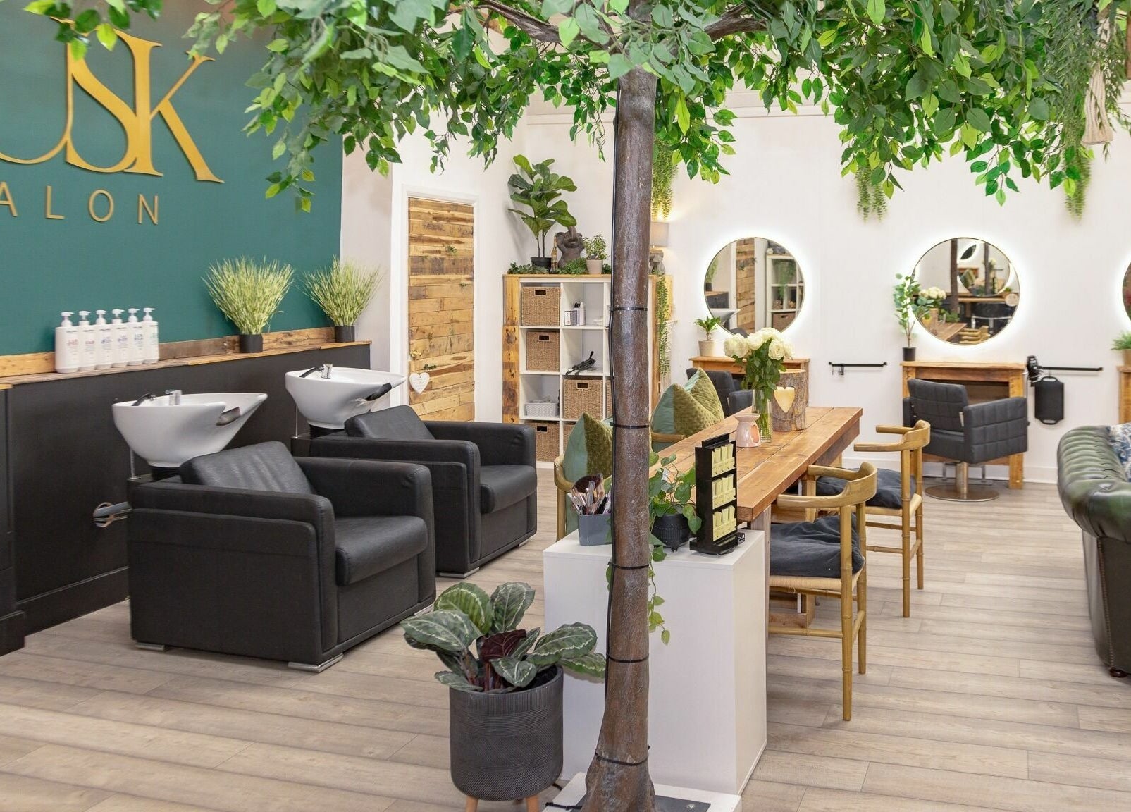 Interior of Tusk Salon in Moreton, England, GB, featuring stylish seating and lush greenery.