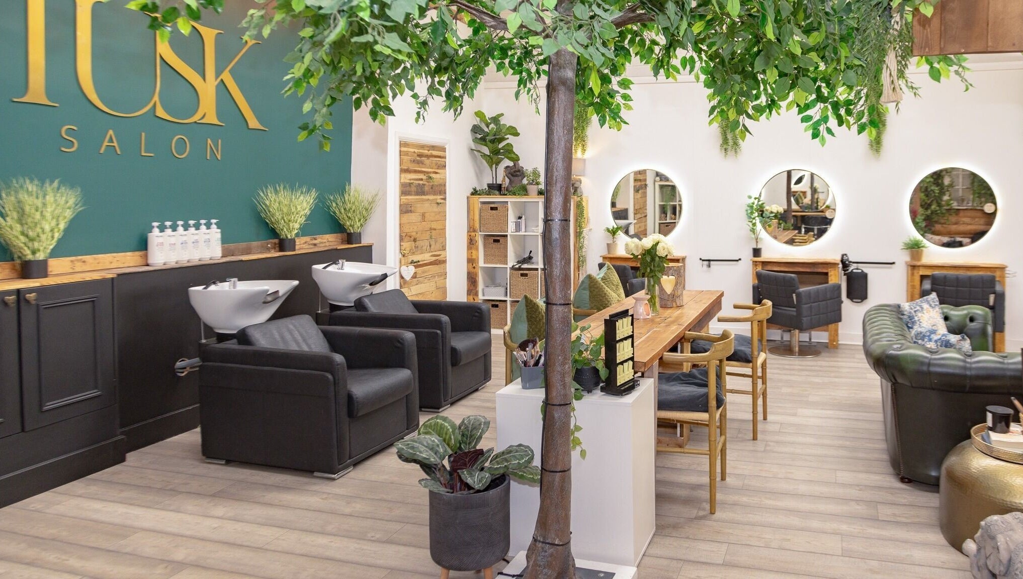 Interior of Tusk Salon in Moreton, England, GB featuring lush plants and styled hair stations.