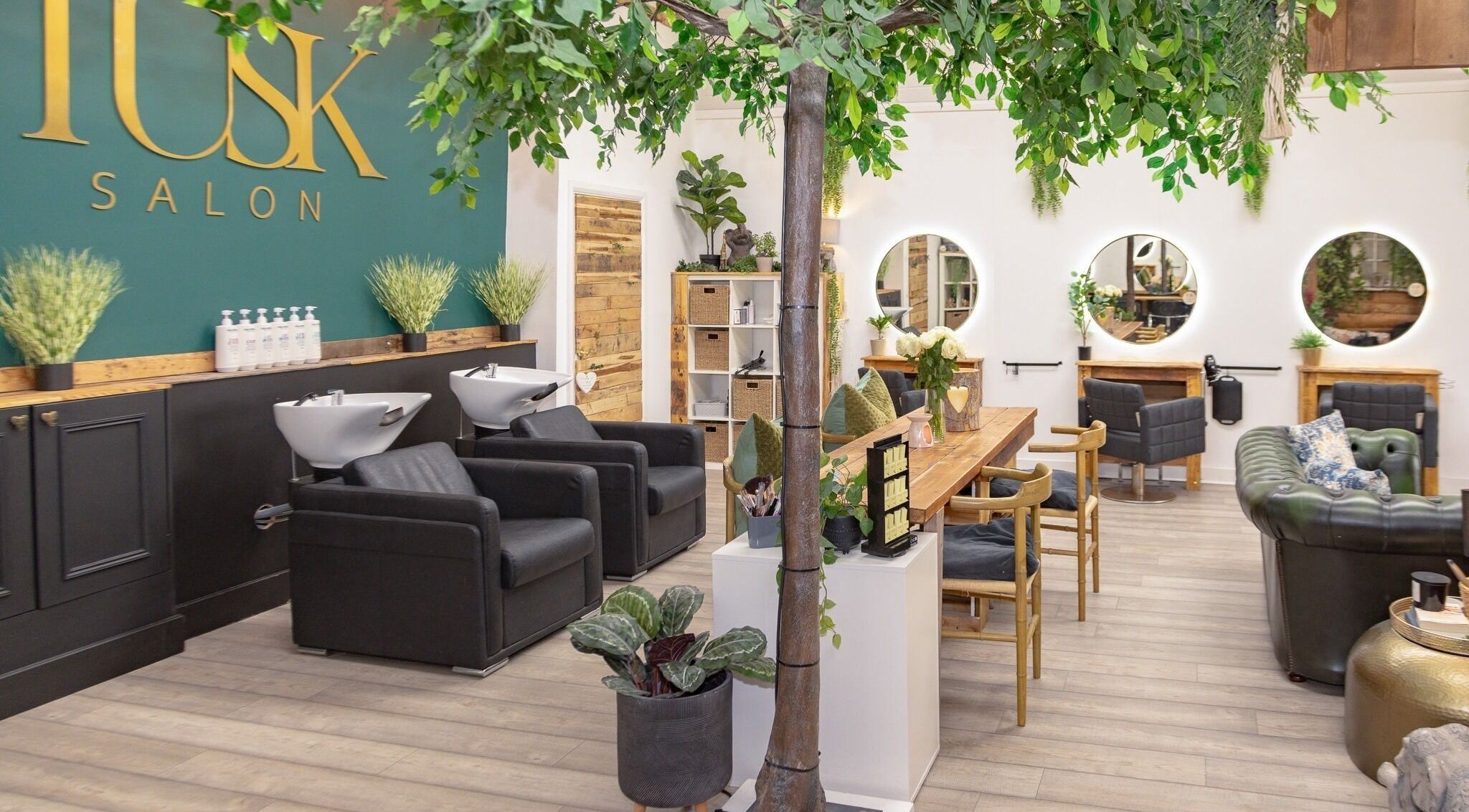 Interior of Tusk Salon in Moreton, England, GB featuring lush plants and styled hair stations.