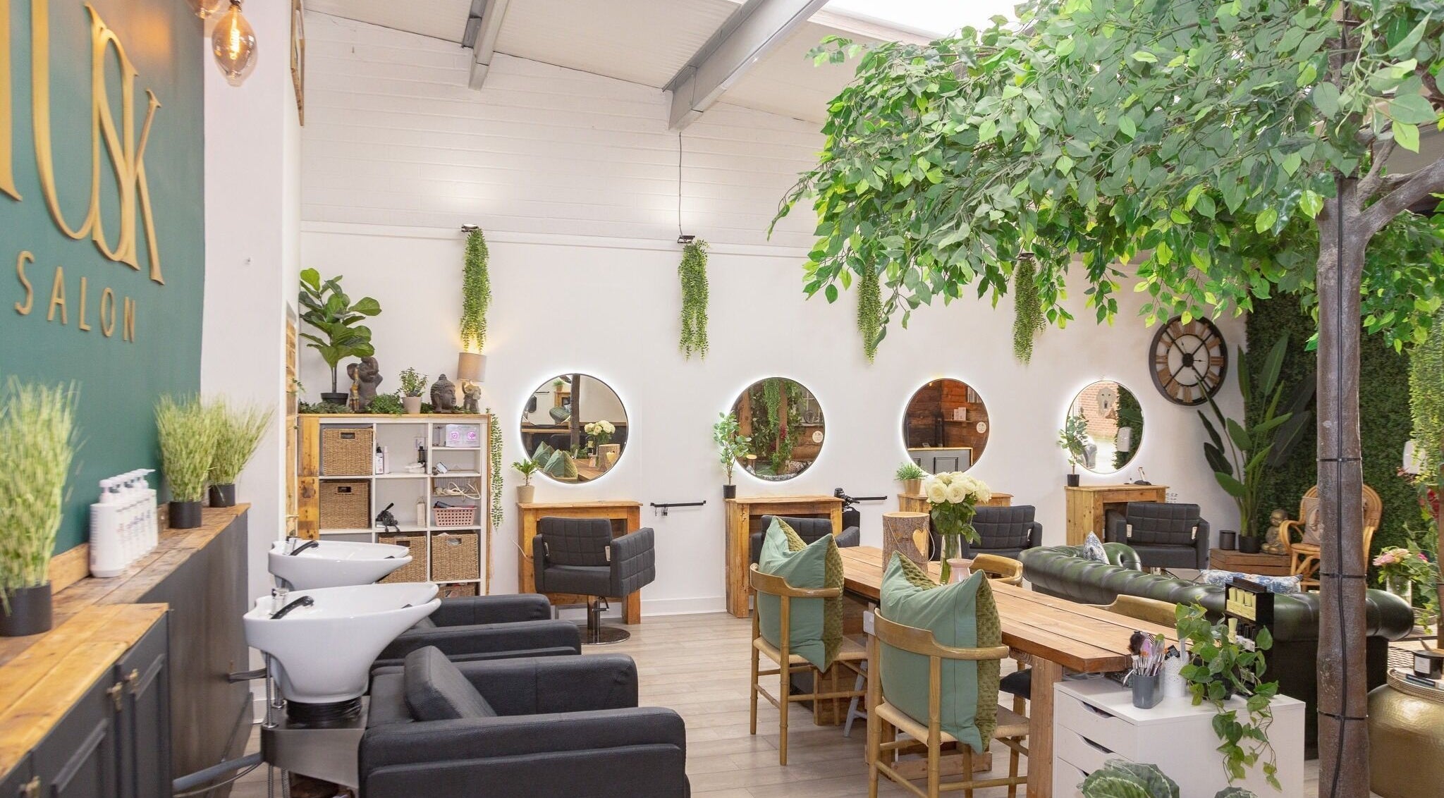 Relaxing interior of Tusk Salon in Moreton, England, GB, featuring elegant mirrors and lush greenery.