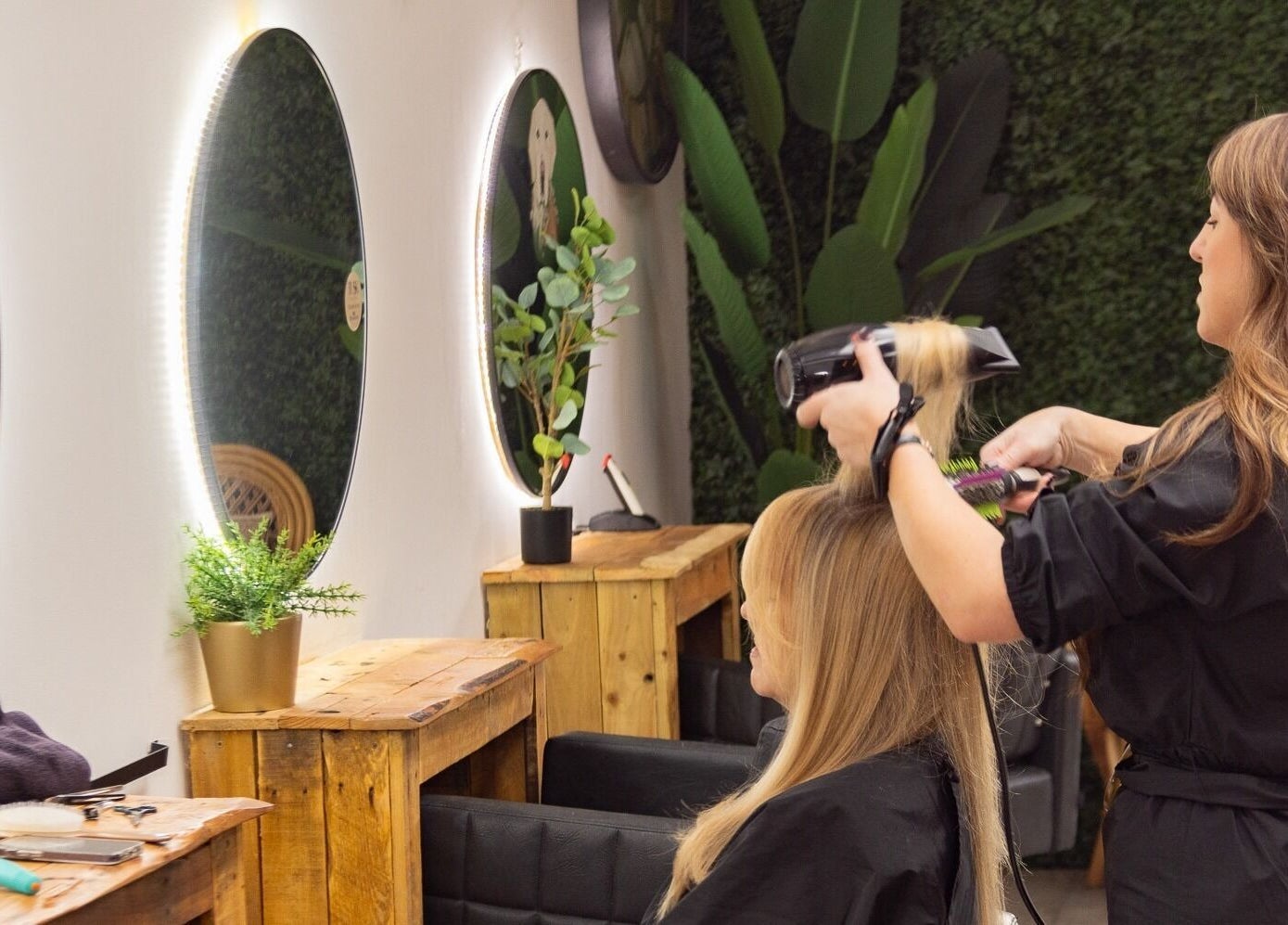 Tusk Salon stylist blow-drying hair inside elegant Moreton, England, GB venue with chic décor.