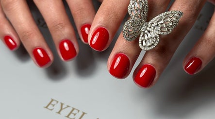 Stylish red manicured nails at Eyelash Secret Ladies Salon Iris Bay, Dubai, Dubai, AE, with a butterfly ring.