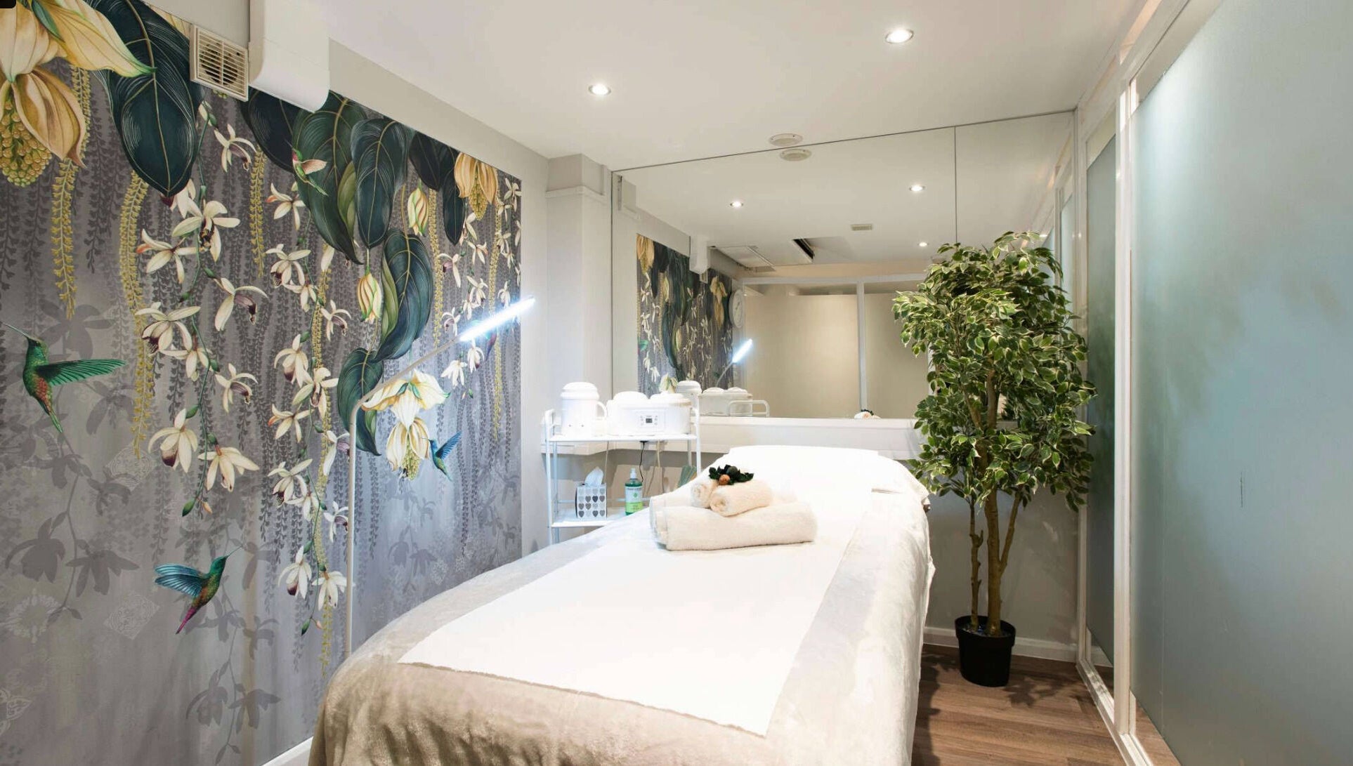 Relaxing therapy room at Anir Anun Clinic, London, England, GB, with floral wallpaper and a treatment bed.