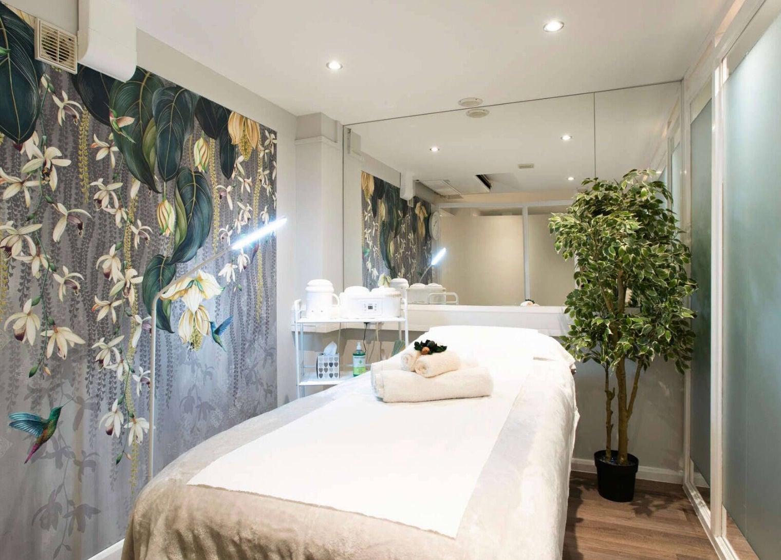 Relaxing therapy room at Anir Anun Clinic, London, England, GB, with floral wallpaper and a treatment bed.
