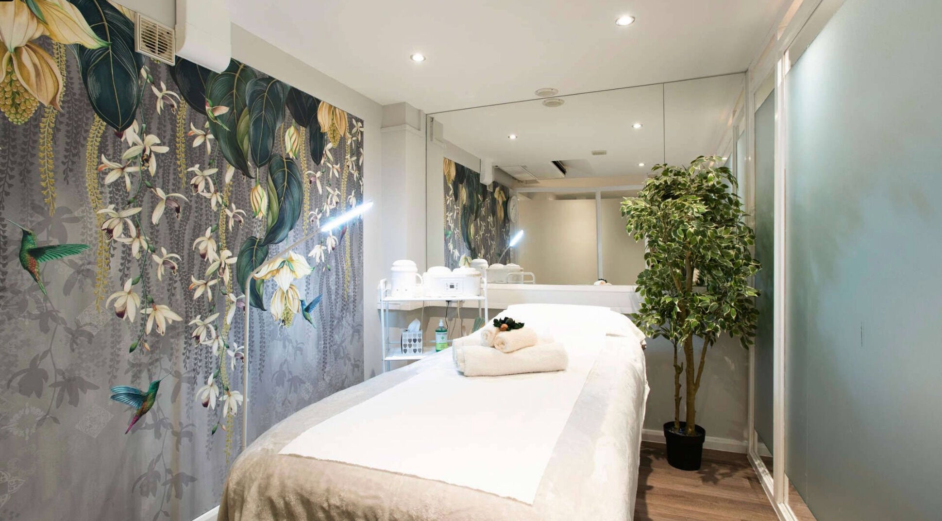 Relaxing therapy room at Anir Anun Clinic, London, England, GB, with floral wallpaper and a treatment bed.