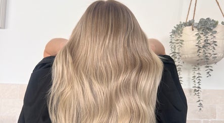 Long, flowing blonde hair styled at Hair by Denielle, Kedron, Queensland, AU, against a serene background.