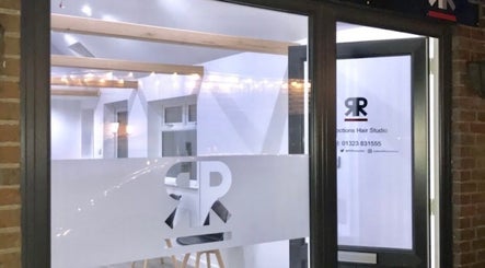 Entrance of Julie at Reflections Hair Studio in Herstmonceux, England, GB at night, with logo on glass.