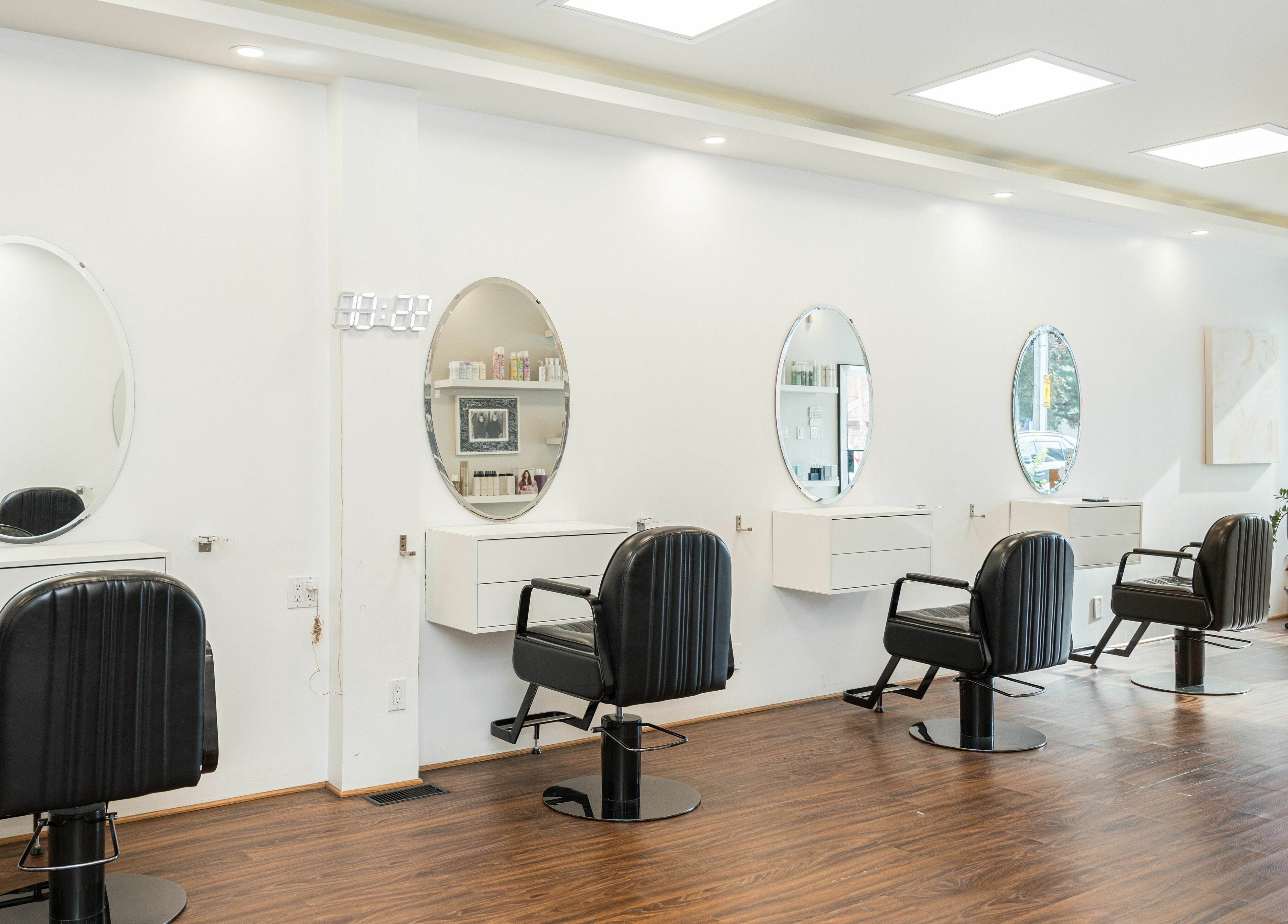 Modern hair salon interior at Twin Scissors, Toronto, Ontario, CA, featuring stylish black chairs and round mirrors.
