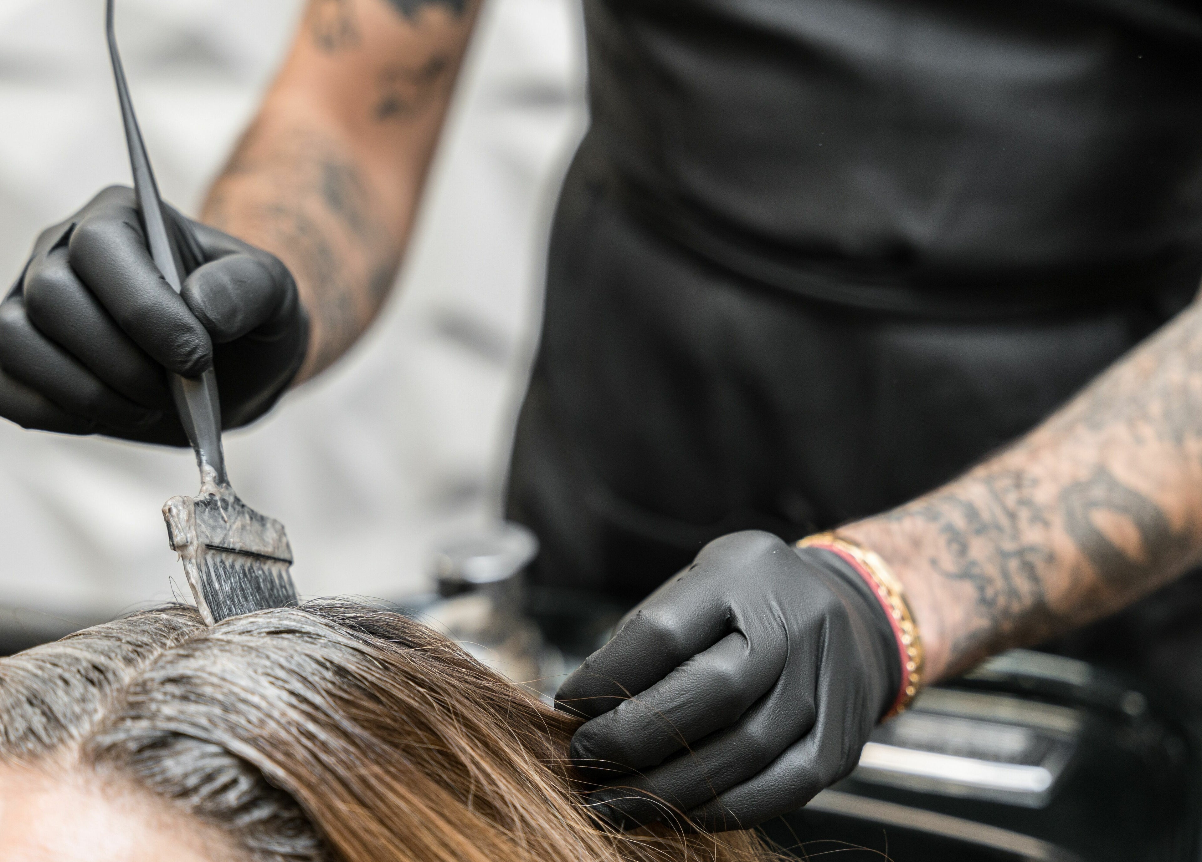 Stylist applying hair color at Twin Scissors in Toronto, Ontario, CA, showcasing expert hair treatment.