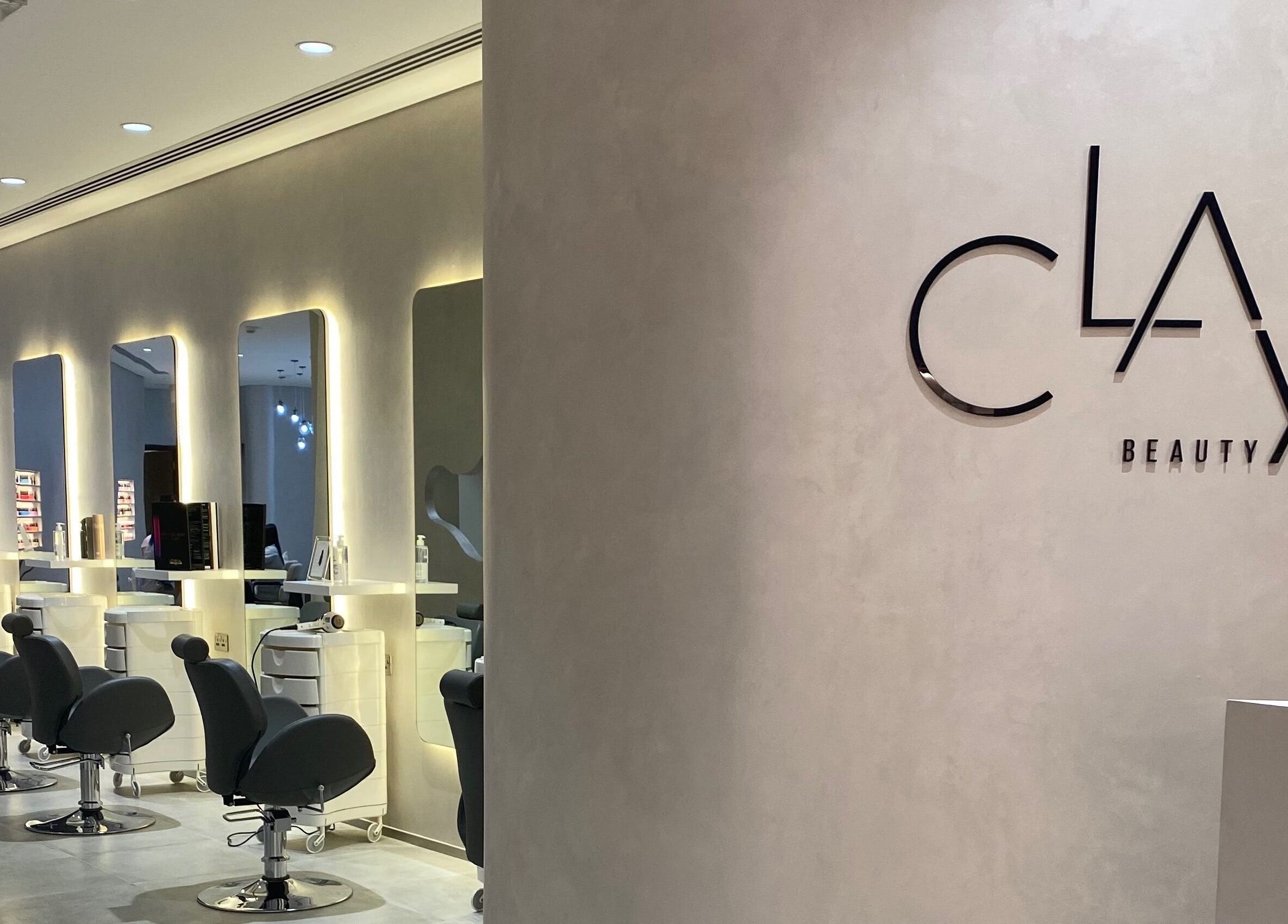Chic interior of Clay Beauty Lounge - Khaldiya in Abu Dhabi, AE, featuring modern salon chairs and illuminated mirrors.